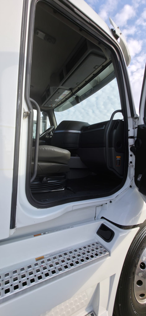 Cab interior of a 2019 Hino 155 box truck showing driver seat, steering wheel, and open door.
