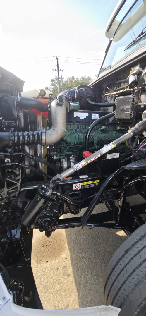 Engine bay of a 2019 Hino 155 box truck showing engine components, hoses, and belts from a side view.