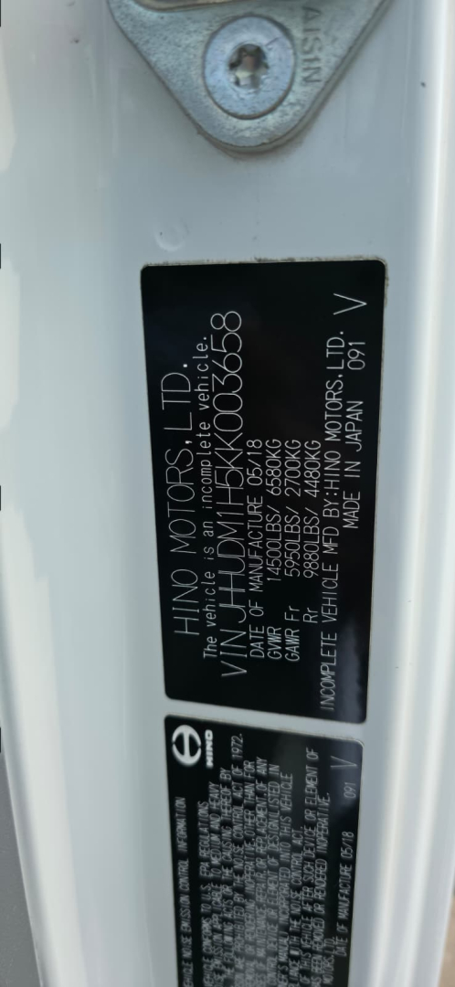Label plate on Hino 155 box truck showing model and VIN details.