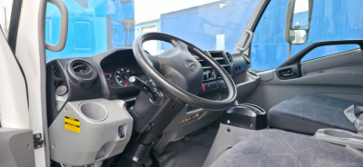 Truck cab interior with steering wheel and dashboard of a 2019 Hino 155, right-hand drive? showing instrument cluster, steering wheel, and gray seats.