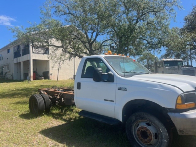 Ford F-550 cab and chassis in profile view showing front cab and exposed chassis rear with dual rear wheels, orange clearance light on roof, white body, black mirrors.