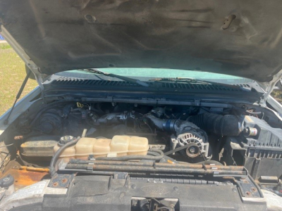 Ford F-550 engine bay with hood open showing coolant reservoir, belts, and air intake; cab and chassis truck in view.