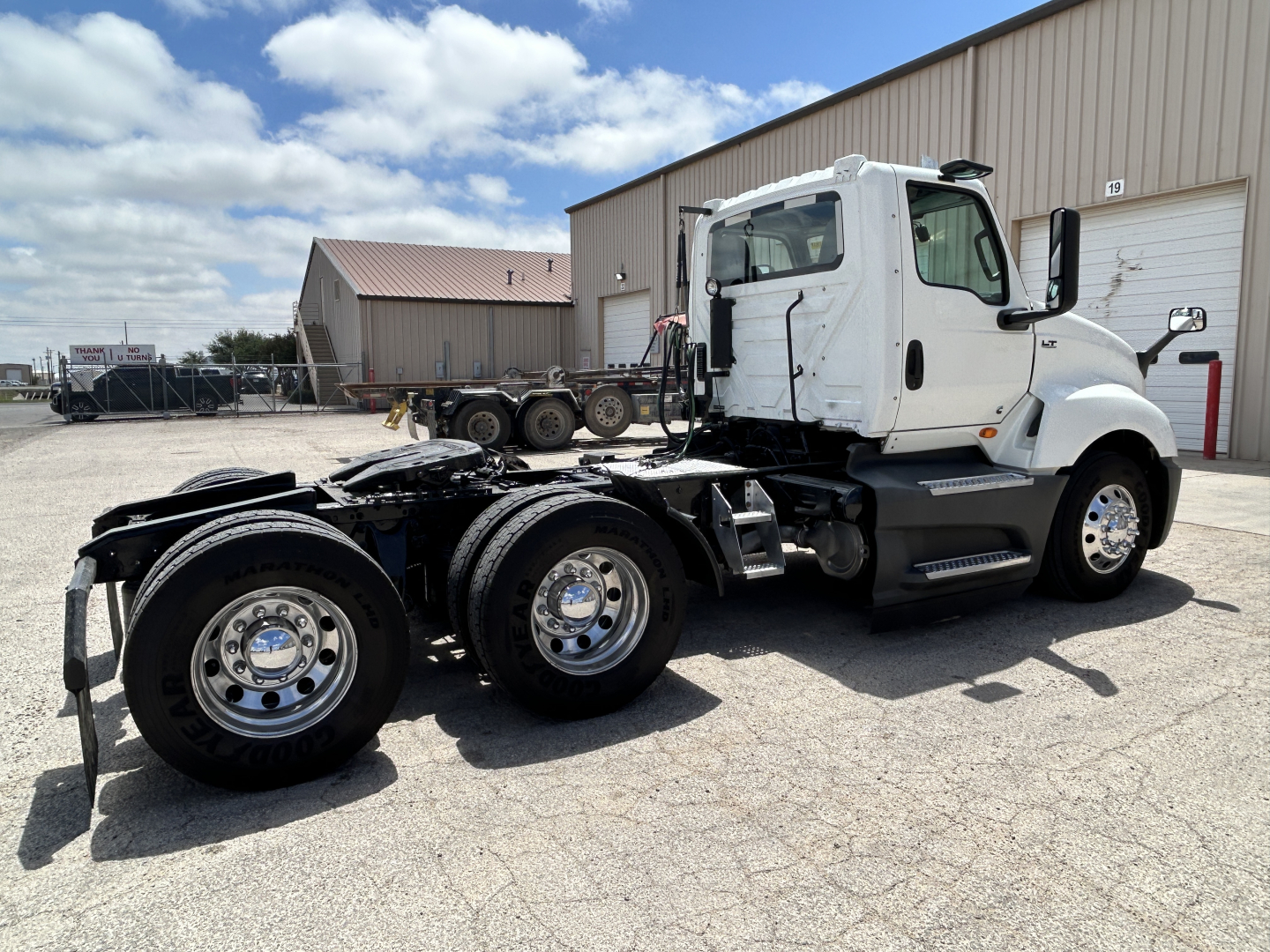 Truck chassis and cab of a 2021 International LT625 conventional daycab viewed from the side showing dual rear axles and white cab.