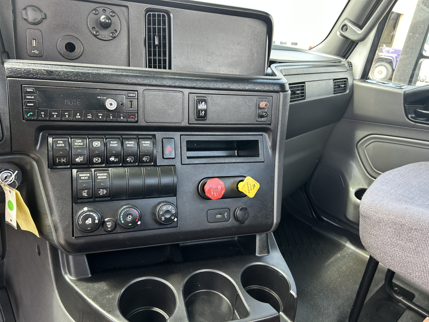 Cab interior of a 2021 International LT625 truck showing gauge panel, climate controls, cup holders, and dashboard switches.