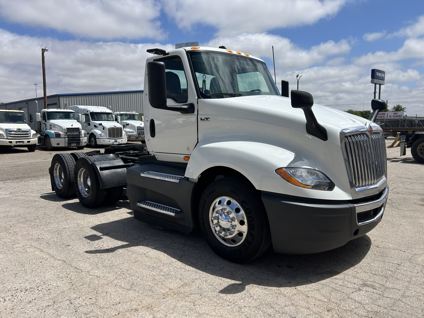 Front-right view of a white 2021 International LT625 daycab truck showing side cab mirrors, chrome front grille, front bumper, wheel wells, and dual rear axles.