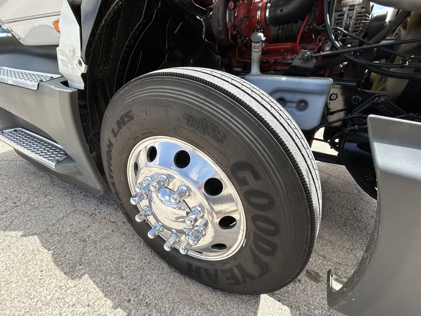 Truck front wheel area showing Goodyear tire and chrome hubcap, engine bay visible in background of a 2021 International LT625 conventional daycab.