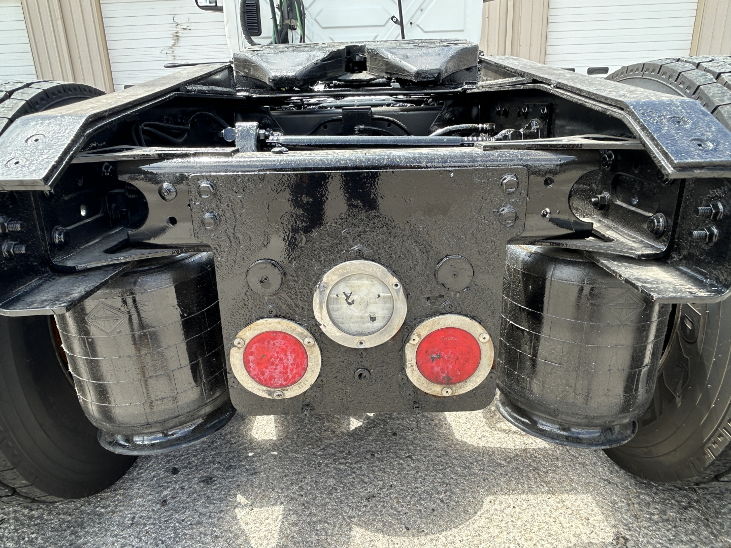 Rear chassis of a 2021 International LT625 tractor showing fuel tanks, mud flaps, and two red circular taillight housings with central circular metal plate.