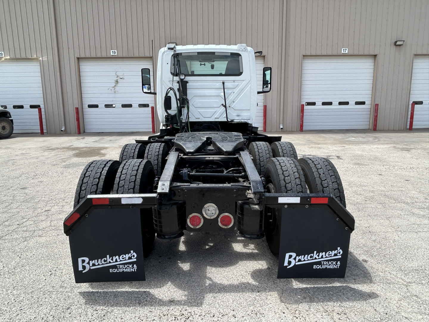 Rear view of a semi truck tractor chassis showing dual rear axles, fifth wheel mount, and mud flaps labeled 'Bruckner's TRUCK & EQUIPMENT' with standard rear lights.