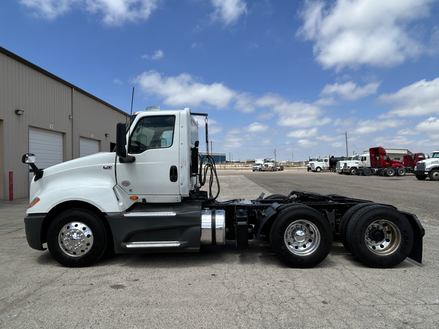 Truck cab and chassis of a 2021 International LT625 in a side view, white cab with dual rear axles, showing mirrors, fuel tanks, and wheel rims.