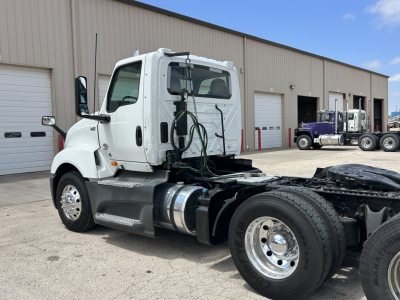 Truck chassis and cab of a 2021 International LT625 Daycab seen from the side, with fuel tank, steps, and dual rear axles; no legible labels visible on the side in this image.
