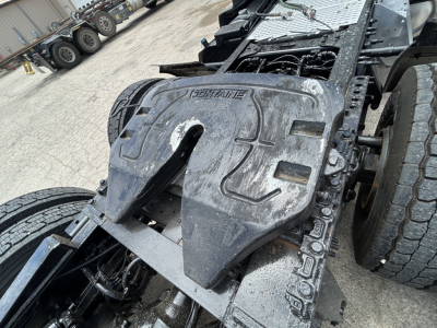Truck engine bay area showing a heavy-duty drivetrain cover with 'JOHNTRACT' embossing? and exposed components near the chassis; dual rear tires visible