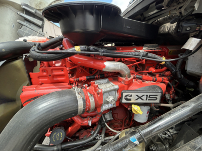Engine compartment of a 2021 International LT625 truck showing a red engine with X15 badge, large intake tube, hoses, and yellow dipstick