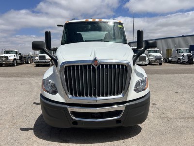 Truck front view showing International LT625 grille with prominent vertical chrome bars, hood emblem, large headlights, black bumper, white cab, and side mirrors; no visible text on components.