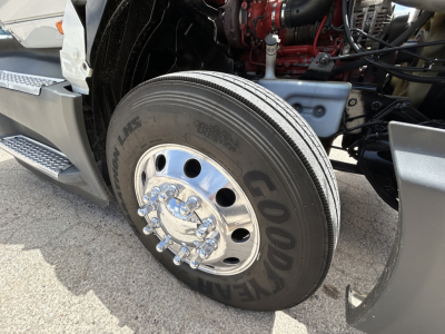 Truck front wheel area showing Goodyear tire and chrome hubcap, engine bay visible in background of a 2021 International LT625 conventional daycab.
