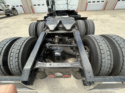 Truck rear chassis with dual rear axles and drivetrain components visible undercab, showing suspension and frame rails.