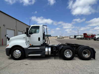 Truck cab and chassis of a 2021 International LT625 in a side view, white cab with dual rear axles, showing mirrors, fuel tanks, and wheel rims.