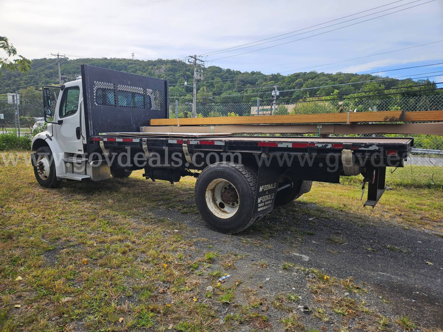 Dump truck bed of a 2004 Freightliner M2 106 with flatbed and metal side rails, white cab, single rear wheel, and frame-mounted utility area.