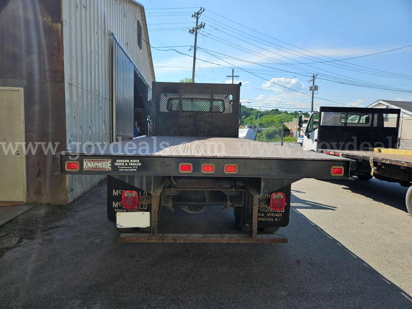 Freightliner M2 106 rear view showing flatbed with taillights and bumper, available in-service, stock number 32136-92, VIN 1FVACXAK44HM56681.