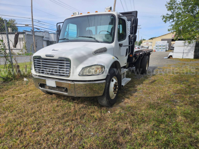 2004 Freightliner M2 106 dump truck with white cab, chrome bumper, and dual rear wheels; visible text includes Freightliner style grille and general exterior features.