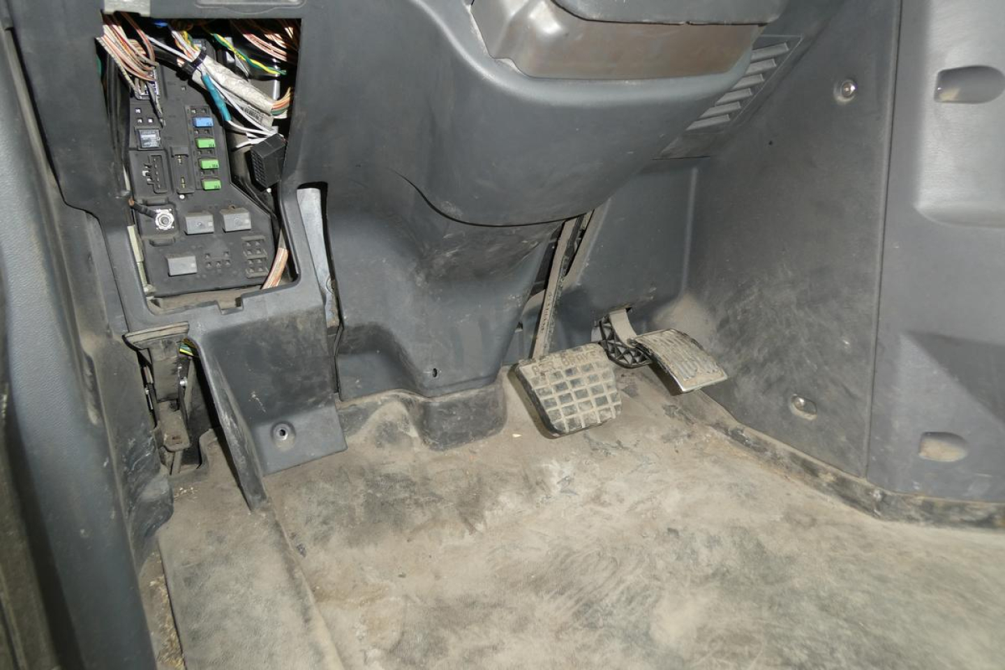 Cab area of a 2018 Mack CXU613T showing pedals and exposed wiring under the dashboard.