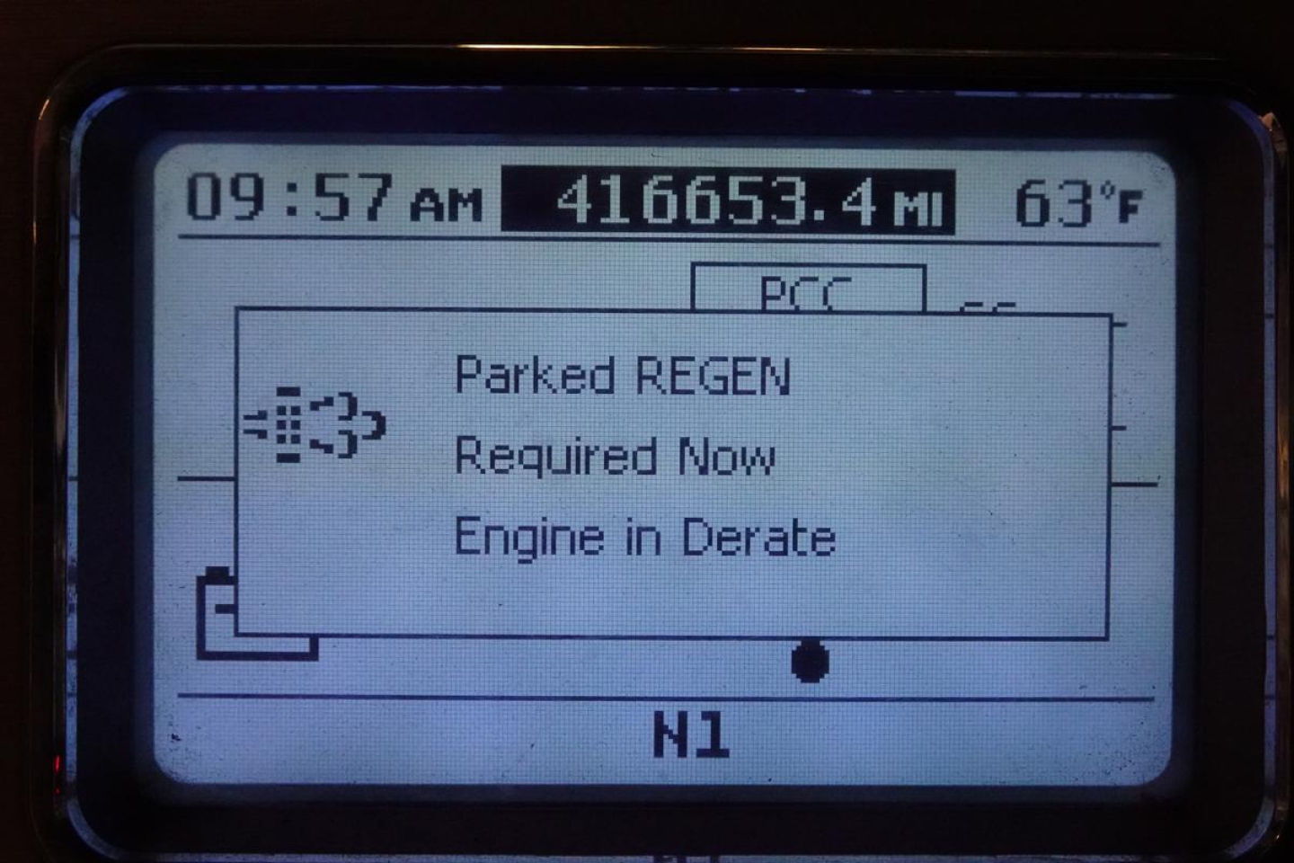 Cab display screen showing time, mileage 416,653.4 mi, outside temperature 63°F, and engine fault notices: Parked REGEN, Required Now, Engine in Derate.
