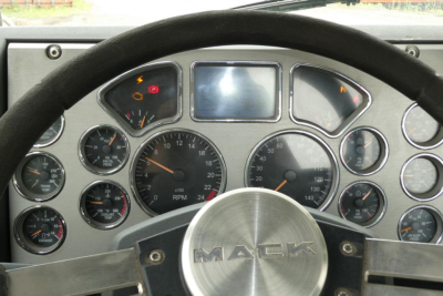Dashboard of a Mack CXU613T truck showing multiple gauges and a center display, steering wheel with Mack logo.