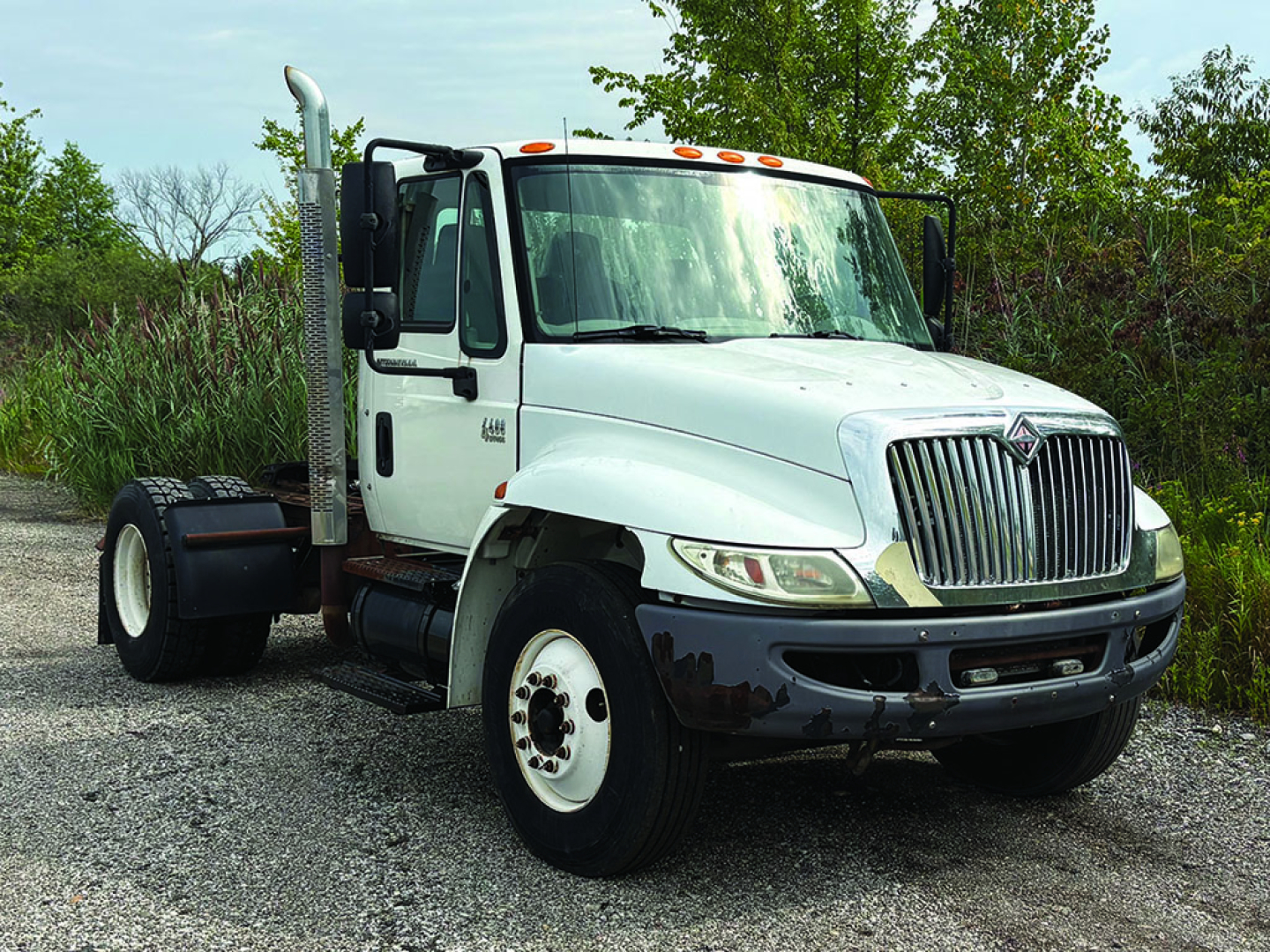 White 2007 International 4400 conventional daycab truck front-left view with chrome grille and dual exhaust, with stock number 557031 and VIN 1HSMKAAN47H474600