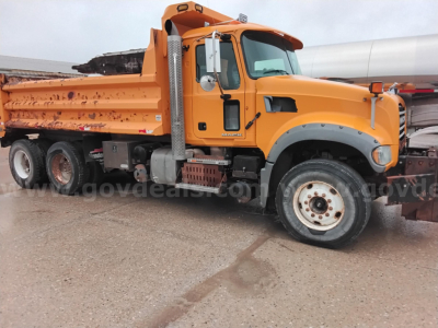Dump truck showing orange Mack GU713 Granite cab and bed with black wheel arches and side exhaust,”