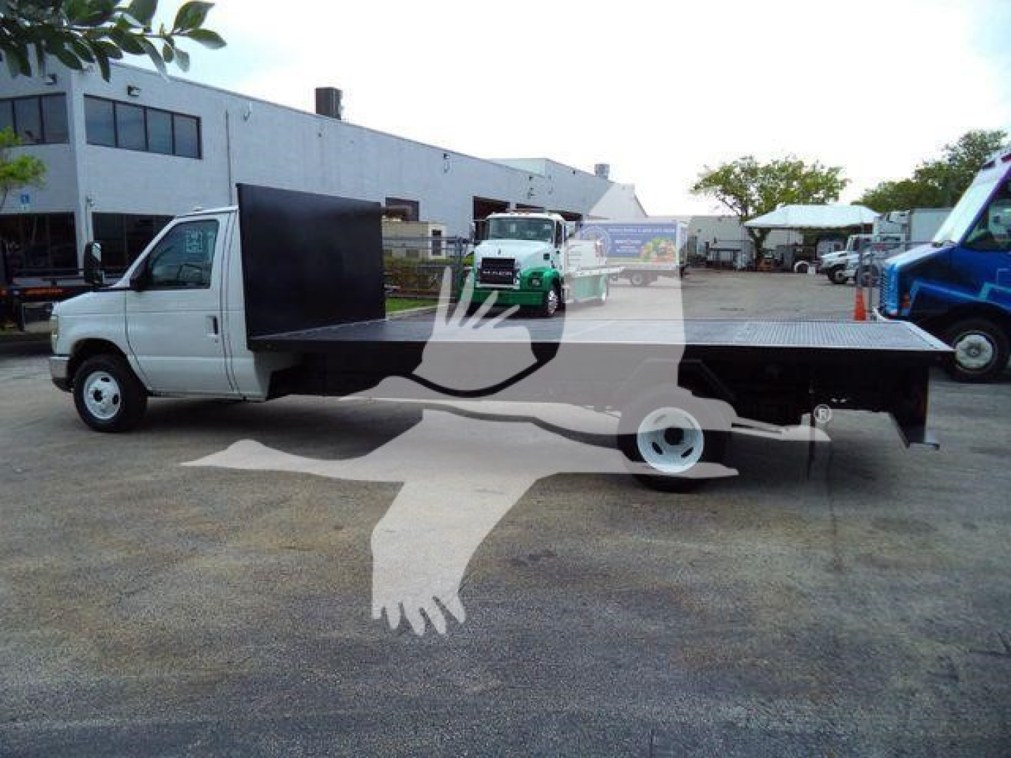 Flatbed truck side view showing 2011 Ford E450 with long black flatbed and white cab.