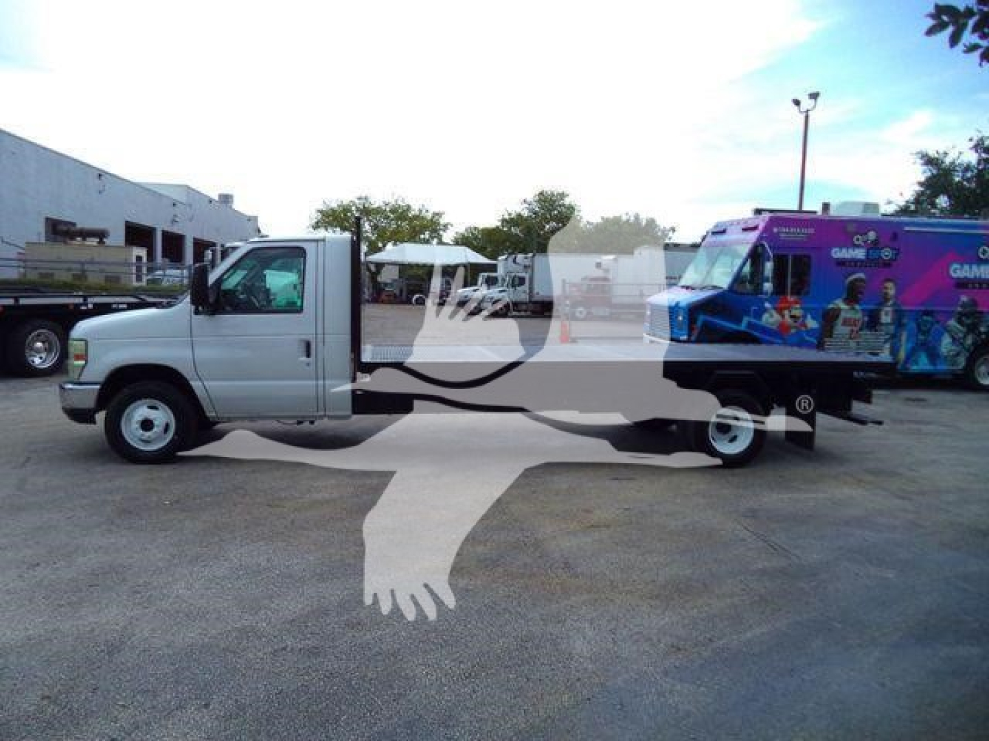 2011 Ford E450 flatbed truck with a white cab and a purple Gameworks-themed vehicle on a flatbed behind; stock number T07531FM; category flatbed; used.