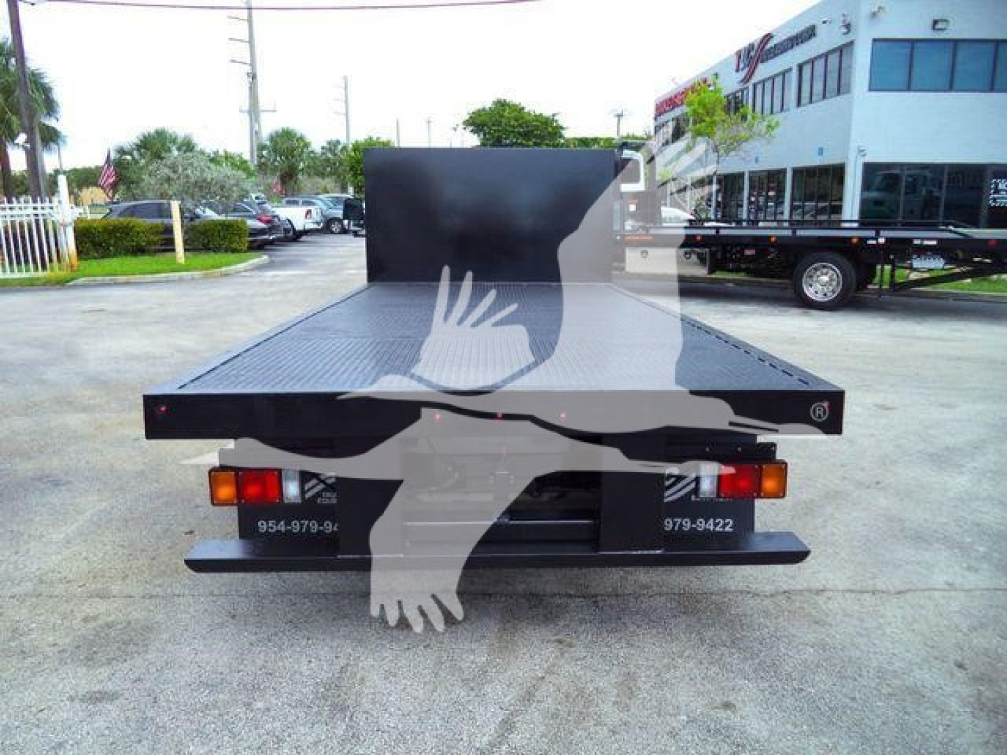 Flatbed truck bed rear view of a 2011 Ford E450 in-service with a black flatbed and tail lights visible.