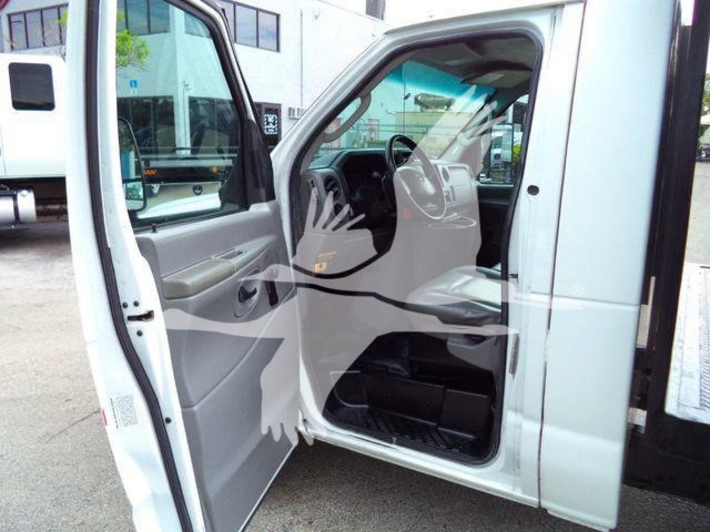 Ford E-450 cab interior and open driver door showing grey plastic panels and steering wheel.