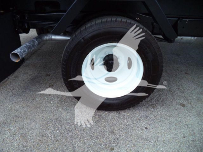 Ford E-450 flatbed truck wheel and exhaust visible, single rear wheel with white steel rim and tire, part of chassis and exhaust pipe.