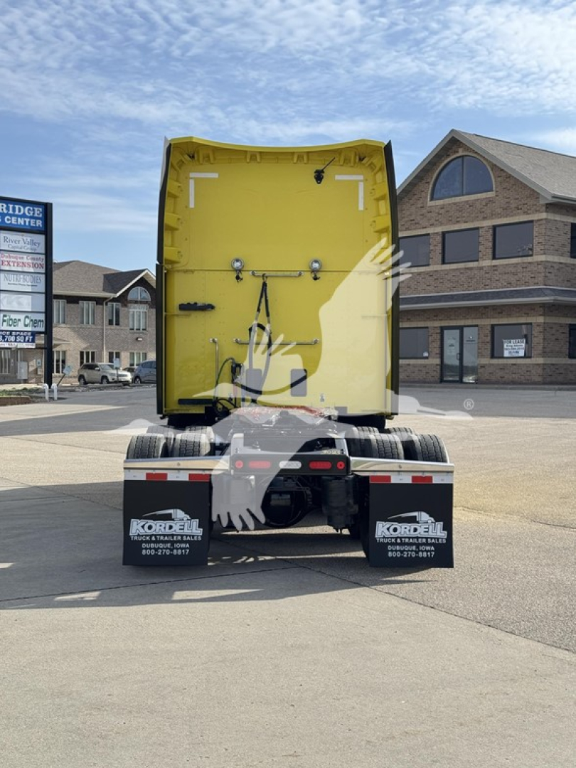 Rear view of a yellow Peterbilt 579 sleeper tractor showing cargo area and rear bumper with mudflaps and license-plate area.