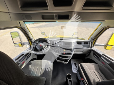 Truck cabin interior view from driver's seat showing steering wheel, dashboard, and center console. Front windshield and side mirrors visible.