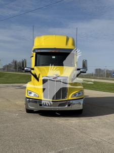 Peterbilt 579 truck front view in yellow with black grille, chrome bumper, and side mirrors.