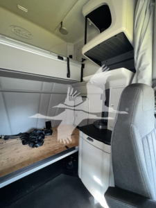 Peterbilt 579 sleeper cab interior showing bunks and storage compartments with light gray surfaces and captain chair.