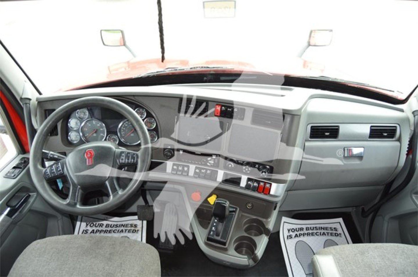 Kenworth T680 cab interior showing steering wheel, dashboard, center console, and gear selector.