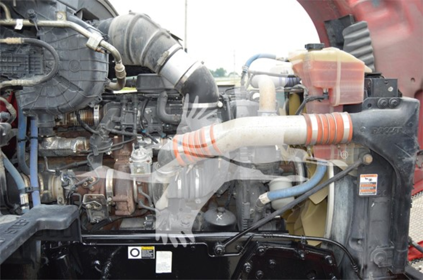 Kenworth T680 engine bay showing coolant reservoir, intake hoses, and radiator components.