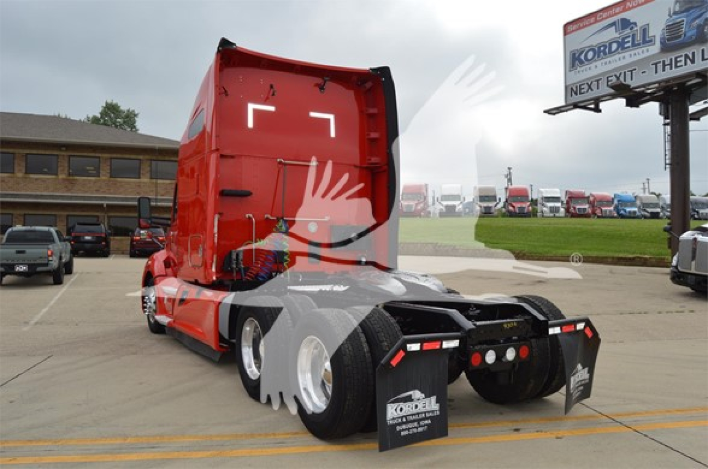 Kenworth T680 truck chassis rear view showing red sleeper cab and black rear with multiple lights; license plate area and mud flaps visible.