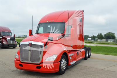 Kenworth T680 sleeper cab truck in red paint with white graphics, front grille, and dual rear axles in a dealership lot.