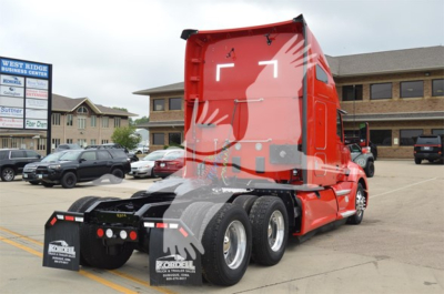 Red Kenworth T680 tractor in a parking lot, rear view showing fifth wheel and dual rear axles. Visible decals: none legible.