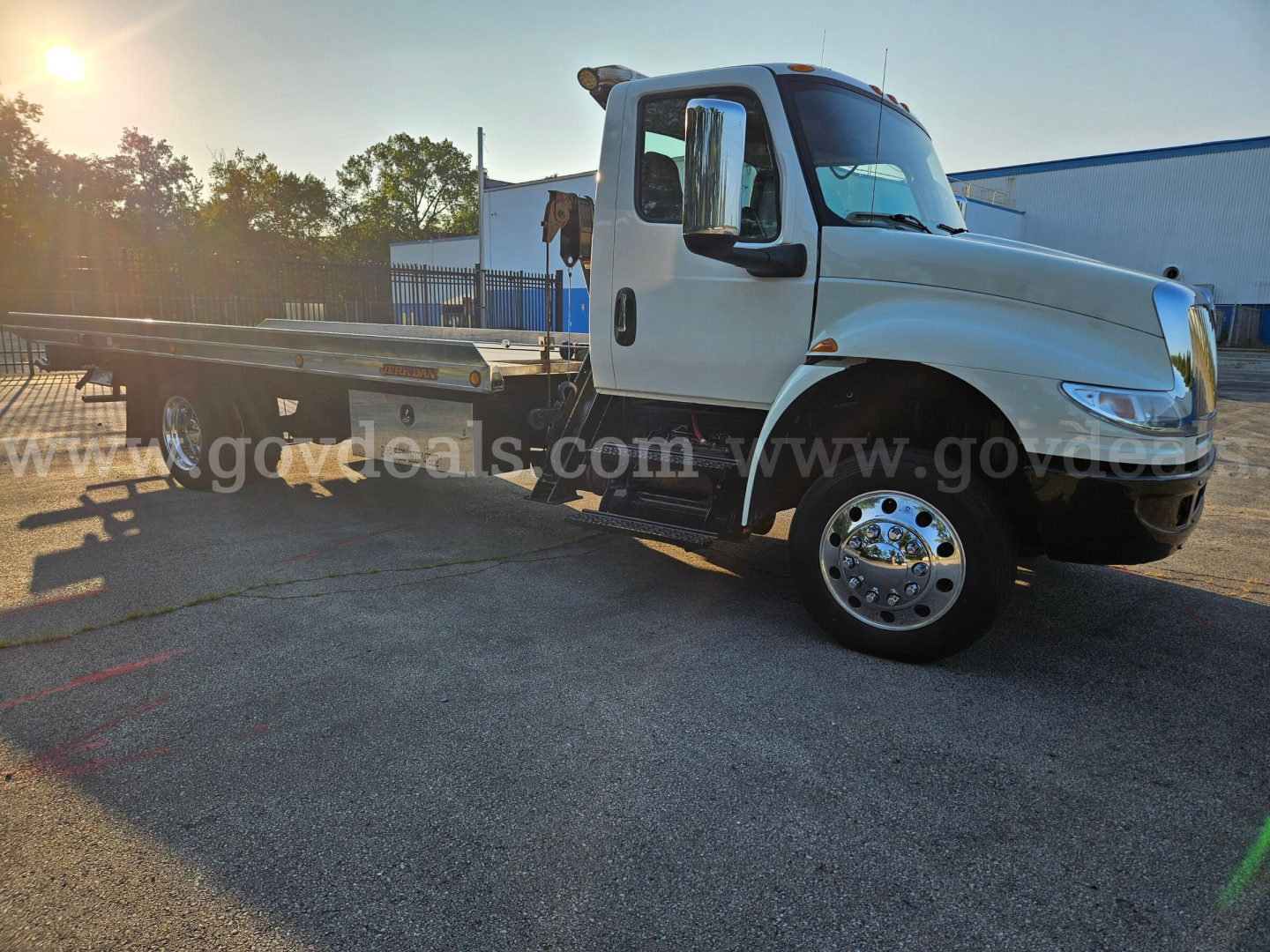 Tow truck chassis side view with flatbed on daylight lot. International MV607 cab, large chrome wheel, white body, VIN 1HTEUMML5KH242148 visible in listing.