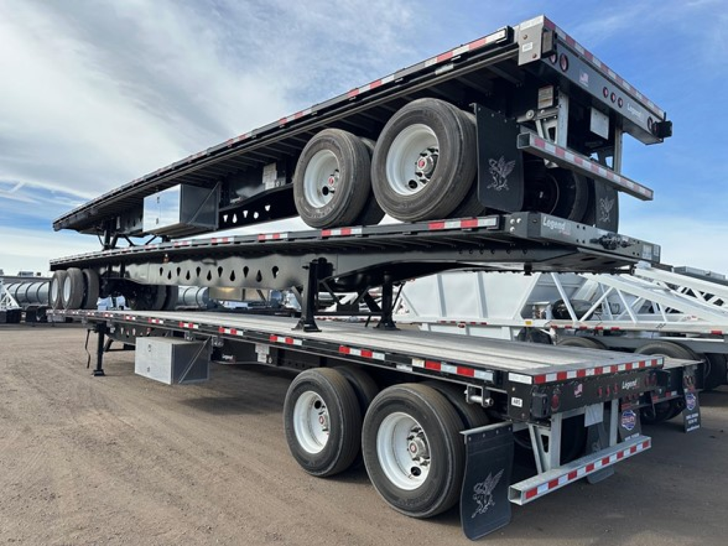 Manac steel 48' flatbed trailer with air ride and air pin slide showing stacked sections on top with dual rear axles and reflective safety markings.