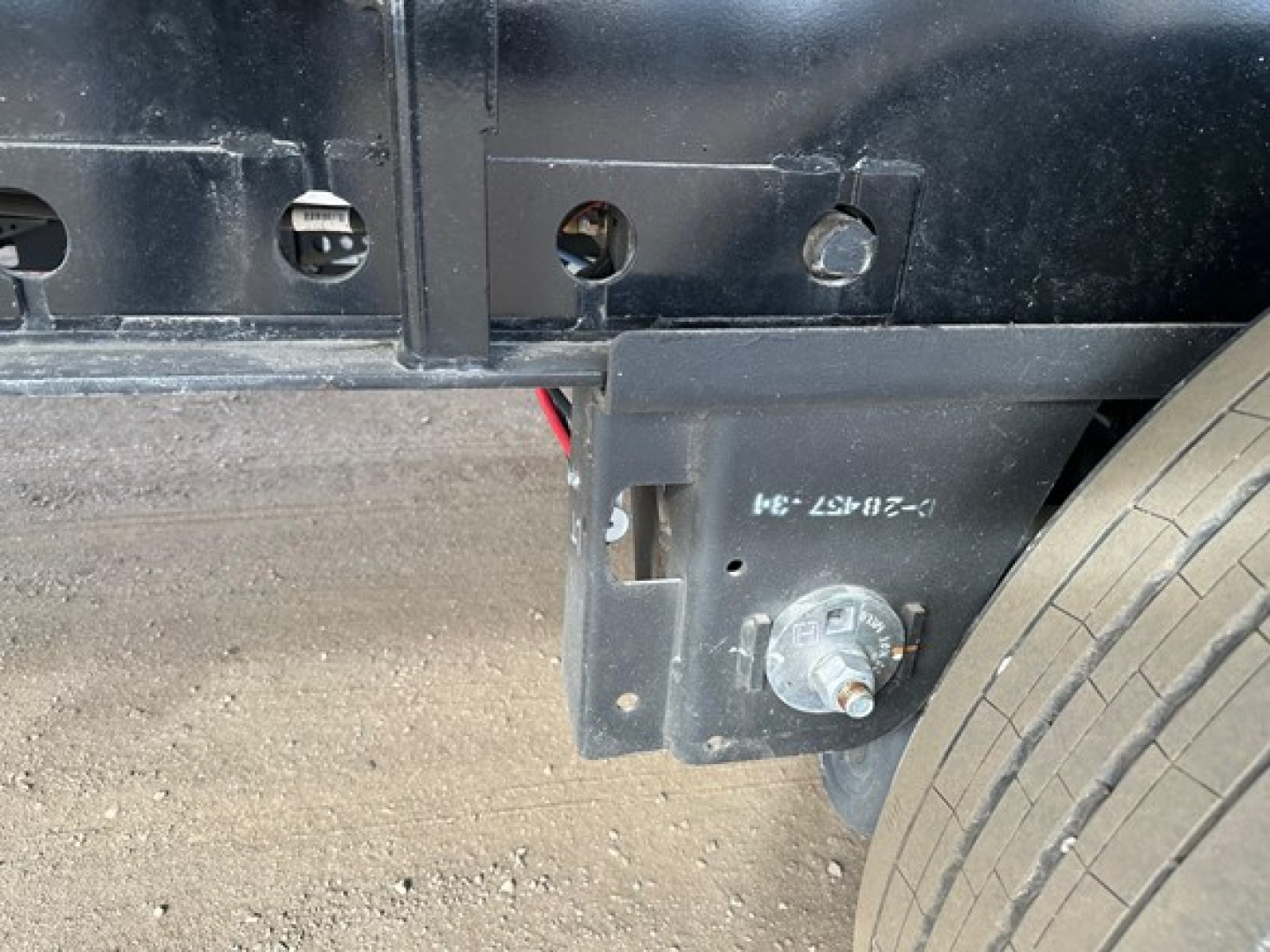 Manac 48' flatbed trailer side view showing suspension mount and wheel, with bolt and mounting plate visible