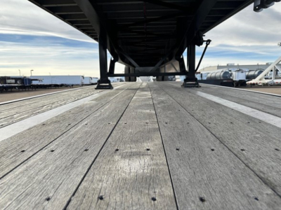 Flatbed trailer deck view from underneath showing wooden planks and air ride components.