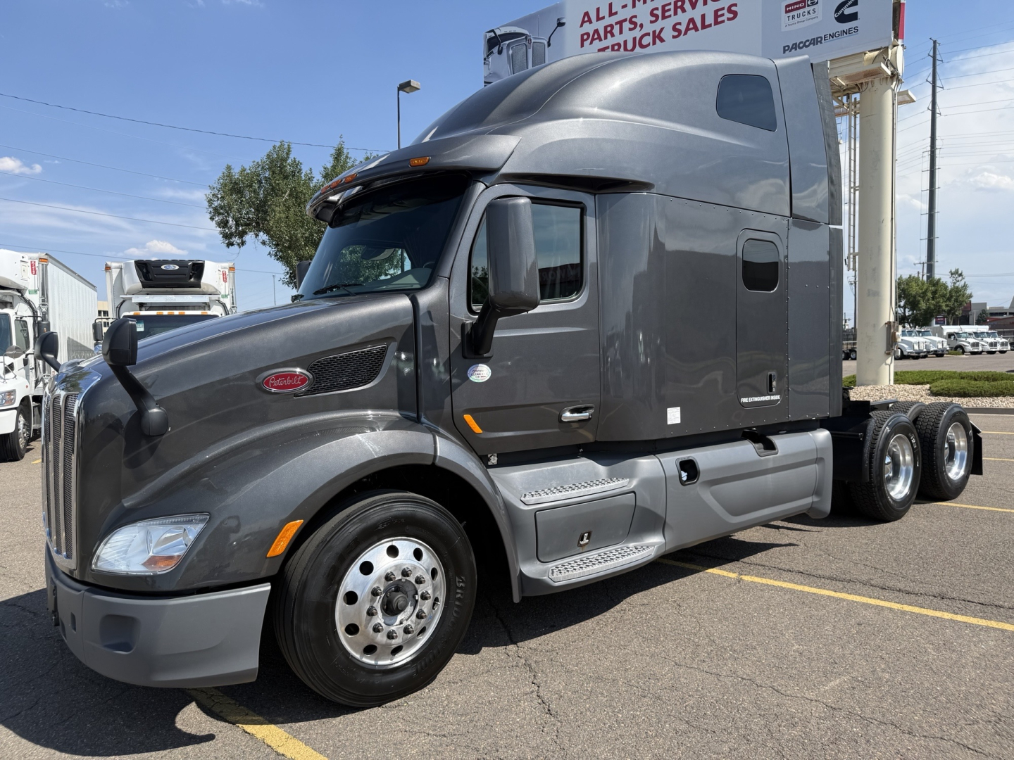 Peterbilt 579 in-service cab with sleeper configuration, front-left view, gray exterior, chrome hubcaps, aerodynamic mirrors, and dual rear axles.