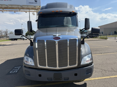 Peterbilt 579 conventional sleeper truck front view showing chrome grille, big windshield, black mirrors, and grey bumper.