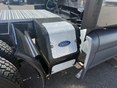 Carrier-branded aluminum toolbox on side of Peterbilt 579 truck, diamond plate surface, adjacent fuel tank and chassis components visible.