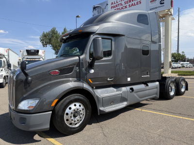 Peterbilt 579 in-service cab with sleeper configuration, front-left view, gray exterior, chrome hubcaps, aerodynamic mirrors, and dual rear axles.